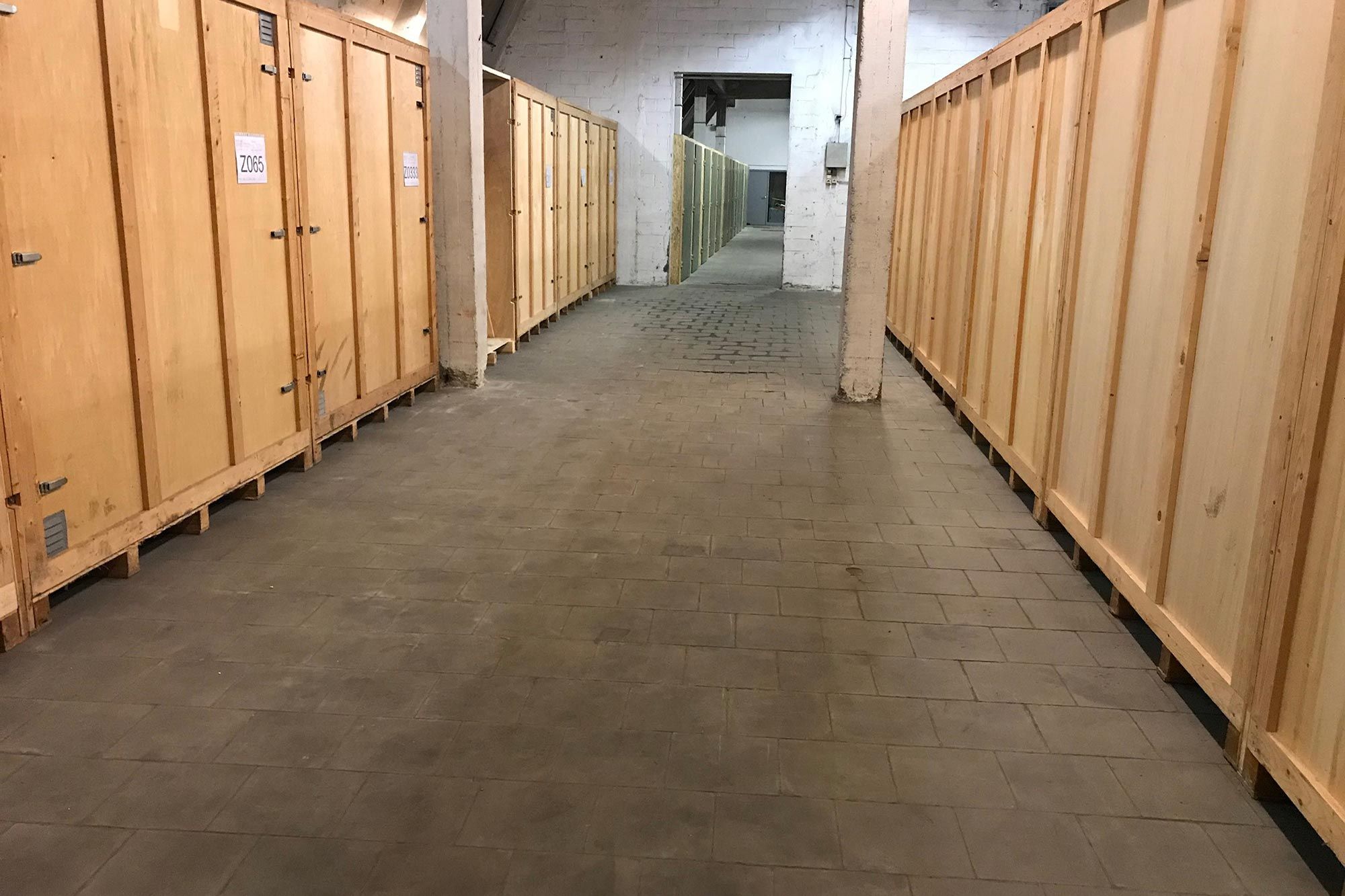 Allée centrale bordée de box de stockage dans un entrepôt Euro Renting Box